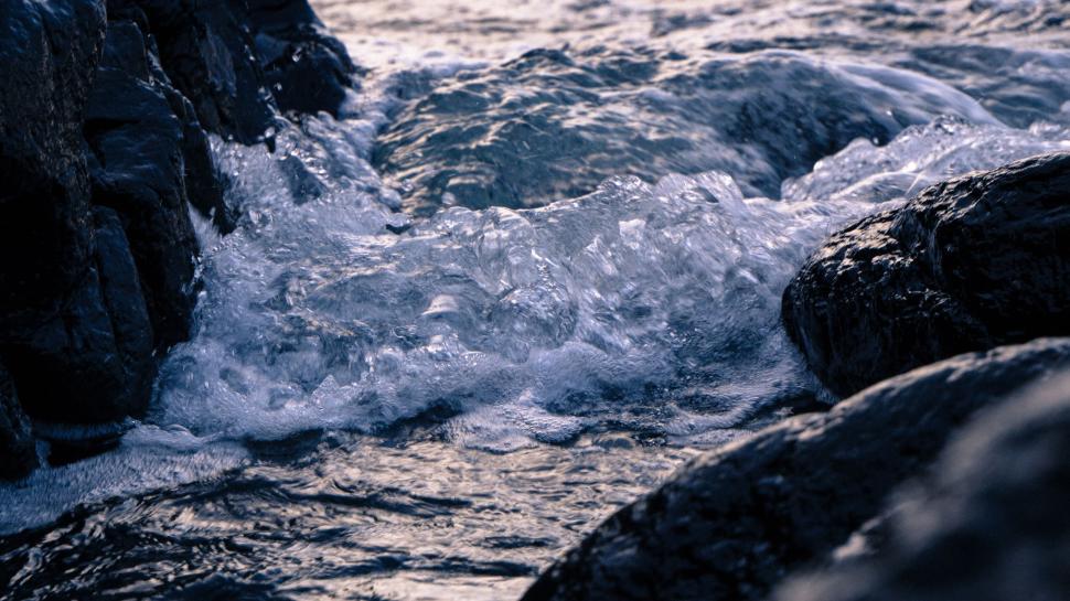Free Image of Close-up of water waves crashing between rocky shores 