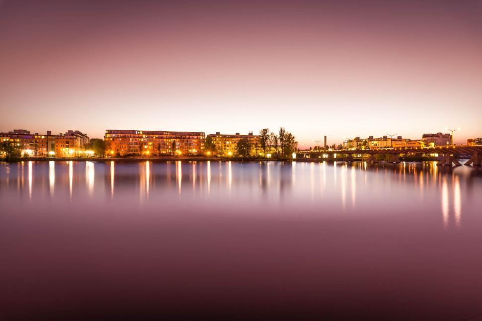 Free Image of Luminous city skyline reflecting on calm river at twilight 