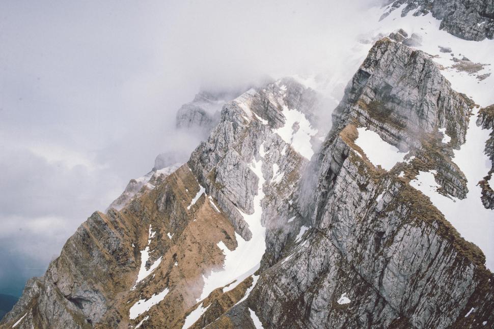 Free Image of Snow-covered rocky peaks in a misty mountain range 