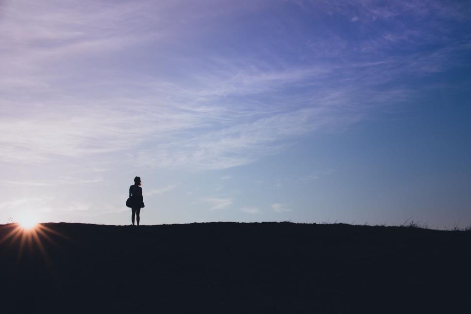 Free Image of Silhouette of a person against a vibrant sunset sky 