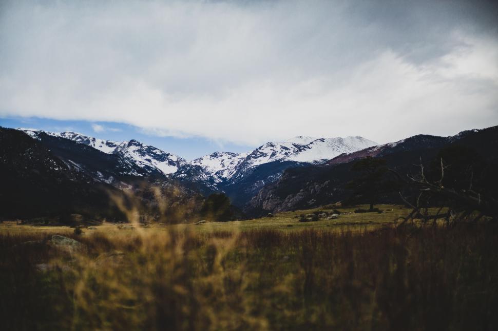Free Image of Snow-capped mountains under a vast, cloudy sky 