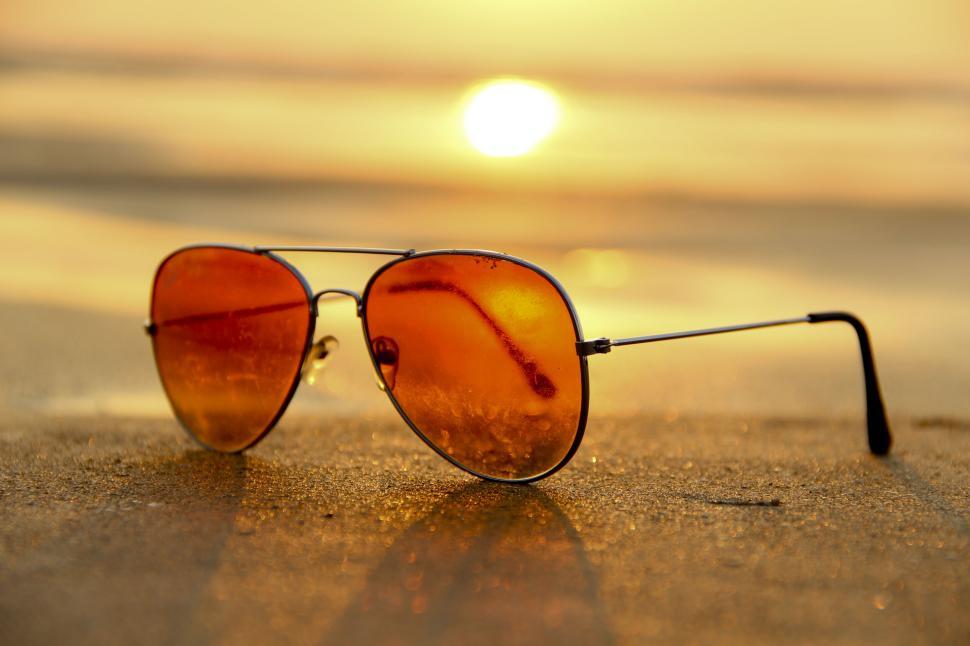 Free Image of Aviator sunglasses reflecting golden beach sunset light 