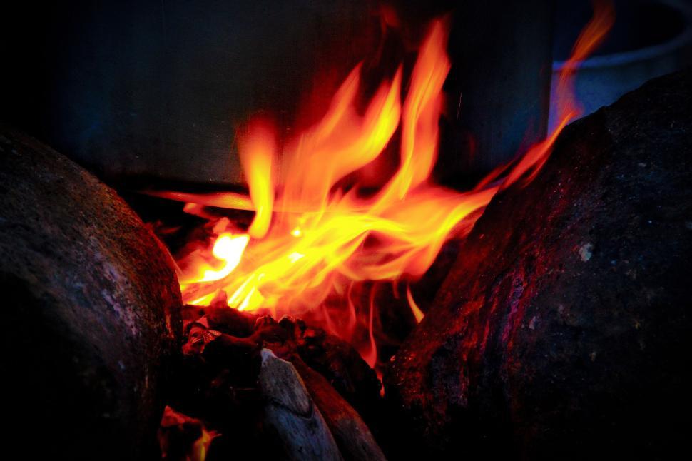 Free Image of Bright, vivid flames dancing between rugged rocks. 