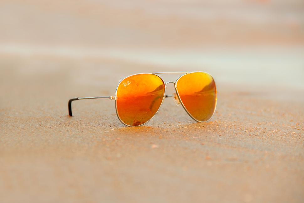 Free Image of Sunglasses resting on sandy beach reflecting sunset glow 