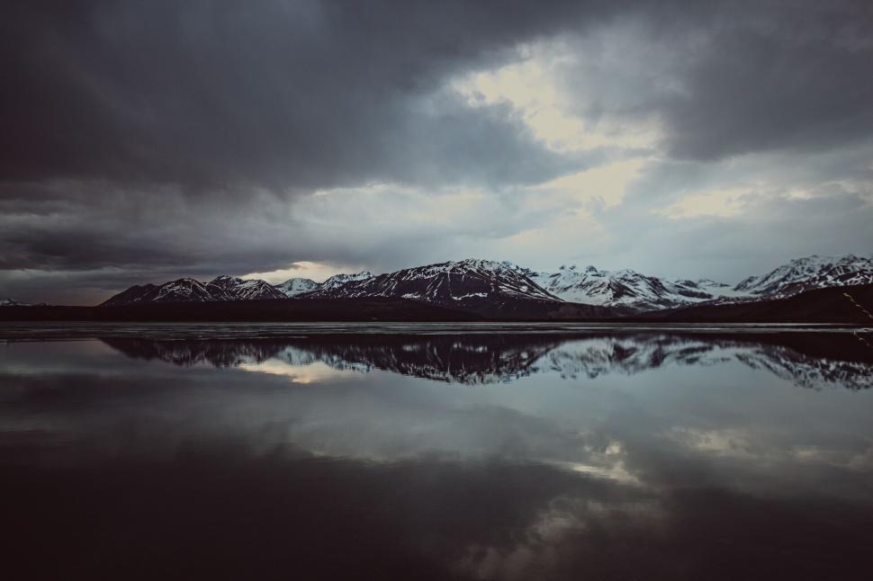 Free Image of Majestic mountain and lake reflection under cloudy sky. 