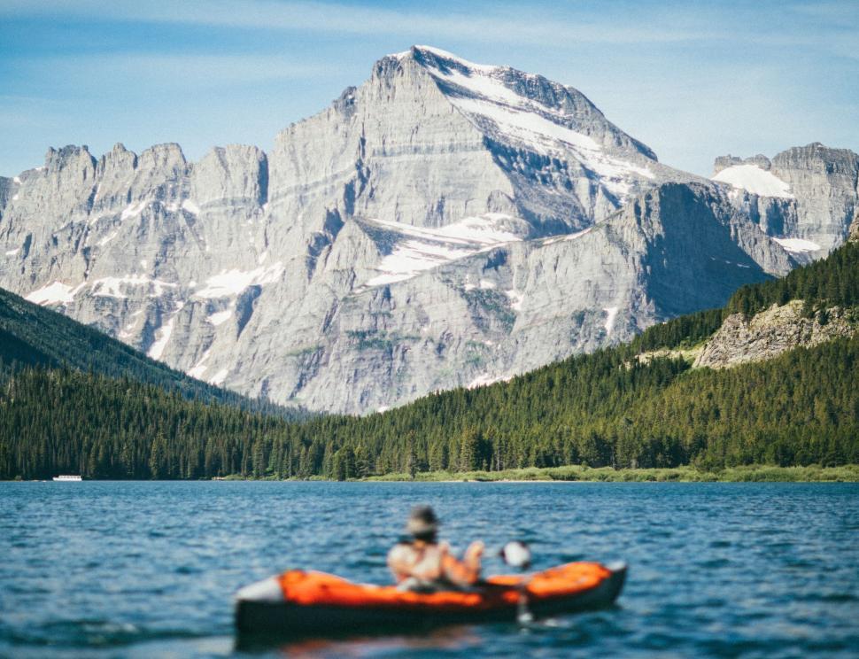 Free Image of Kayakers paddling on a clear lake with snowy mountains 