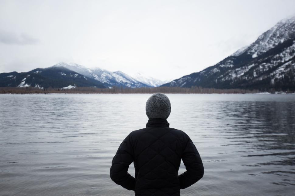 Free Image of Person standing by a peaceful lake with snowy mountains 