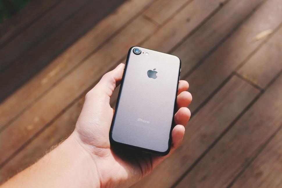 Free Image of Hand holding an iPhone in natural outdoor setting 