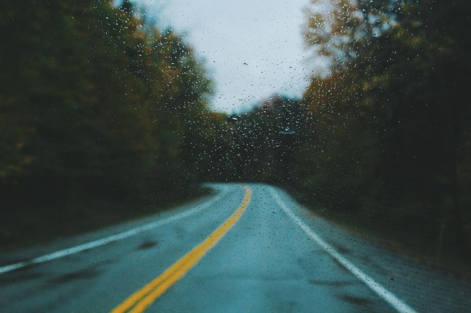 Free Image of Raindrops on windshield with winding road ahead 