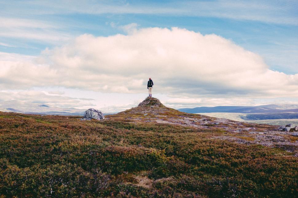 Free Image of Person standing alone on a hill overlooking vast land. 