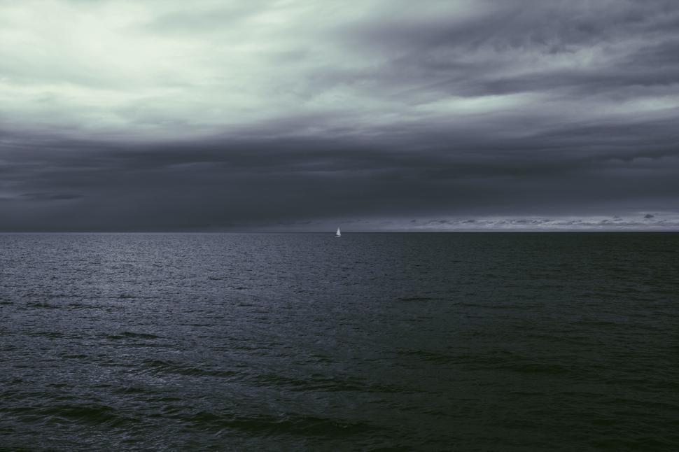 Free Image of Sailboat on a calm ocean under a moody sky 