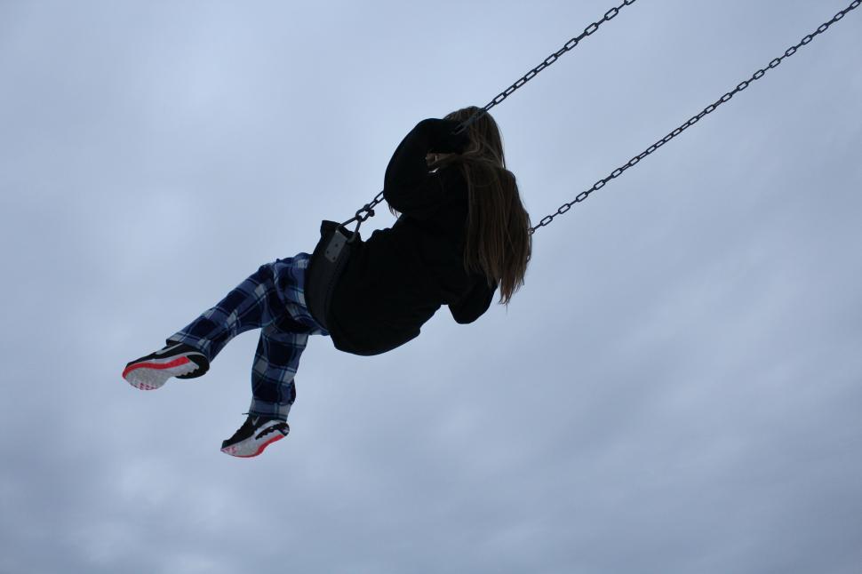 Free Image of Person swinging high in the air against a cloudy sky. 
