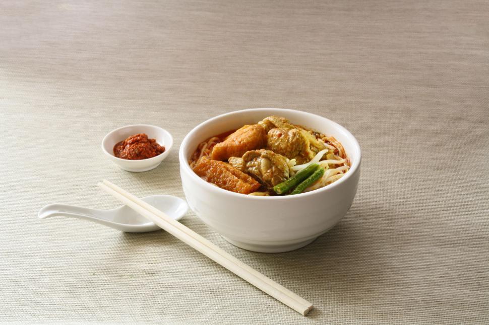 Free Image of Bowl of steaming Asian noodles with wooden chopsticks beside. 