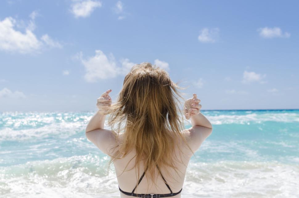 Free Image of Woman facing turquoise sea under bright blue sky 