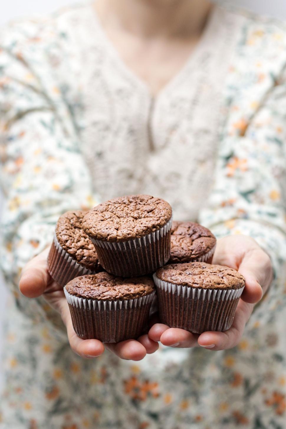 Free Image of Person holding a stack of homemade chocolate muffins. 