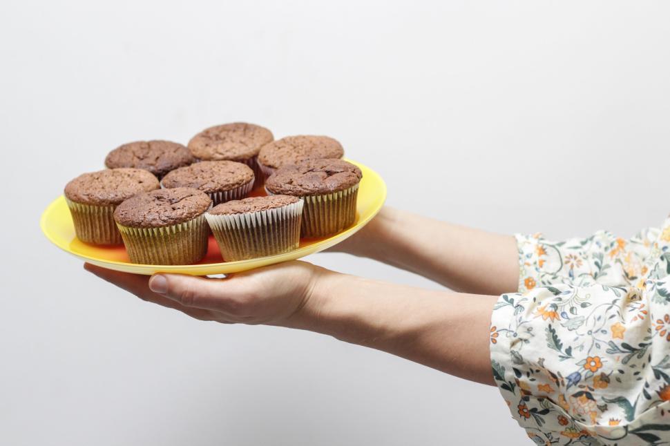 Free Image of Person holding a platter of freshly baked muffins. 