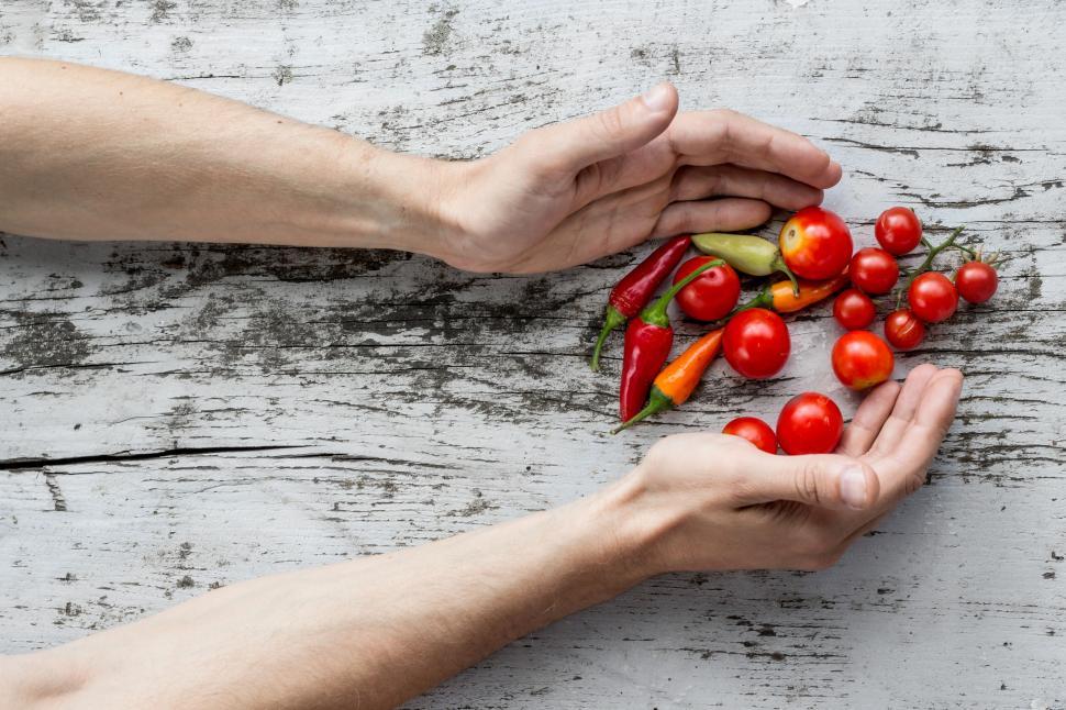 Free Image of Hands arranging fresh tomatoes and peppers on table 