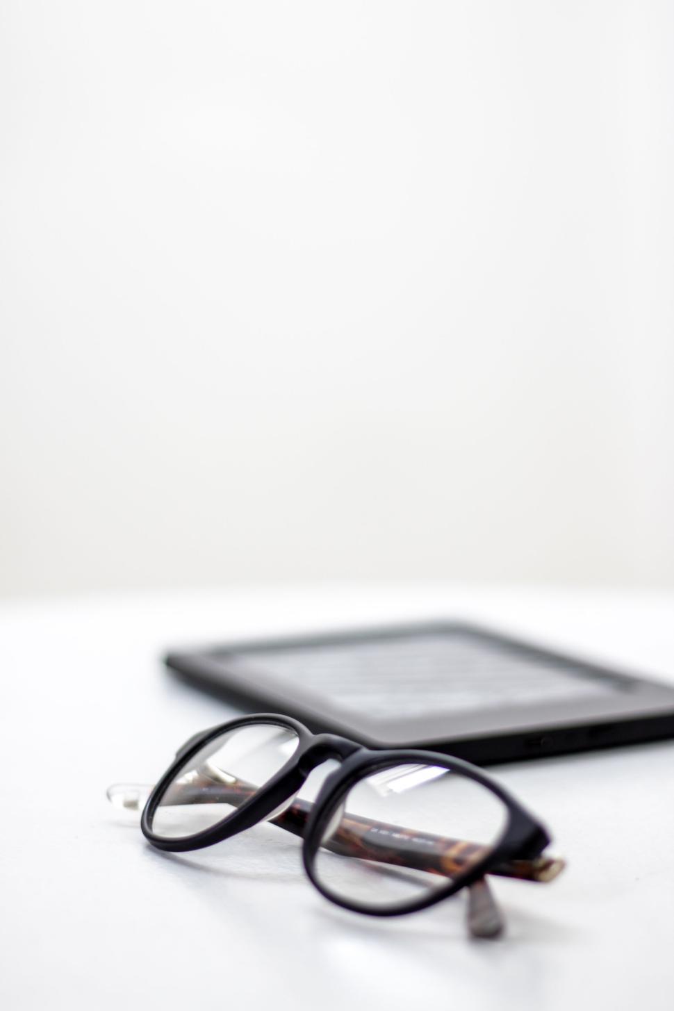 Free Image of Close-up of black glasses and electronic device on table 