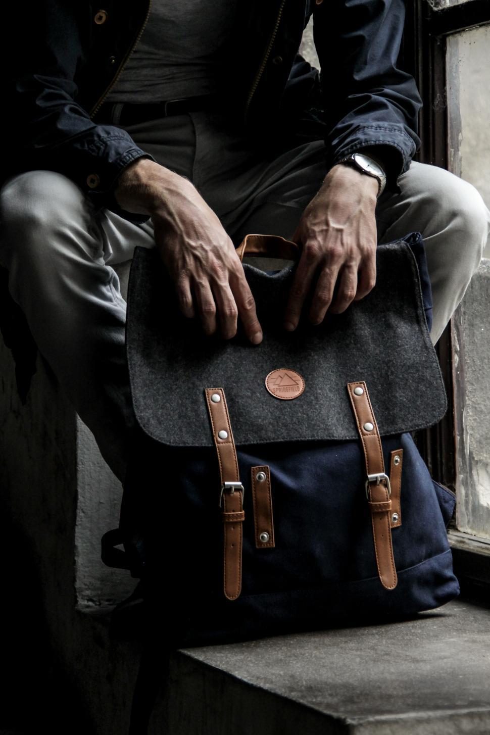 Free Image of Person sitting with a stylish black and brown backpack. 