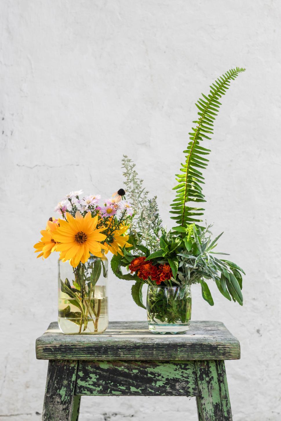 Free Image of Bouquets of flowers with fern in glass vases on stool 