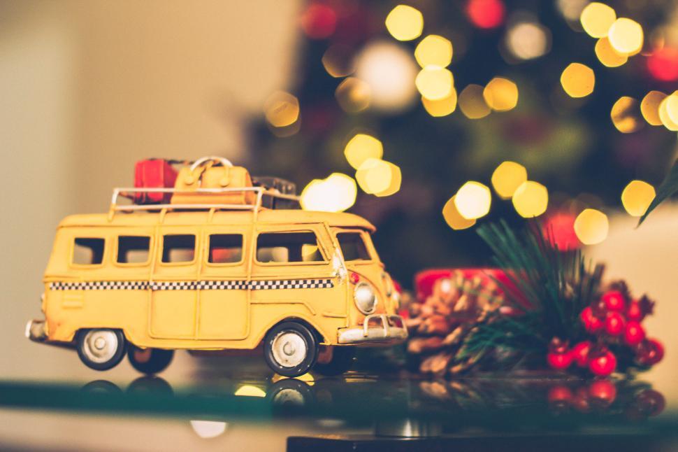 Free Image of Yellow toy bus with gifts in front of Christmas tree. 