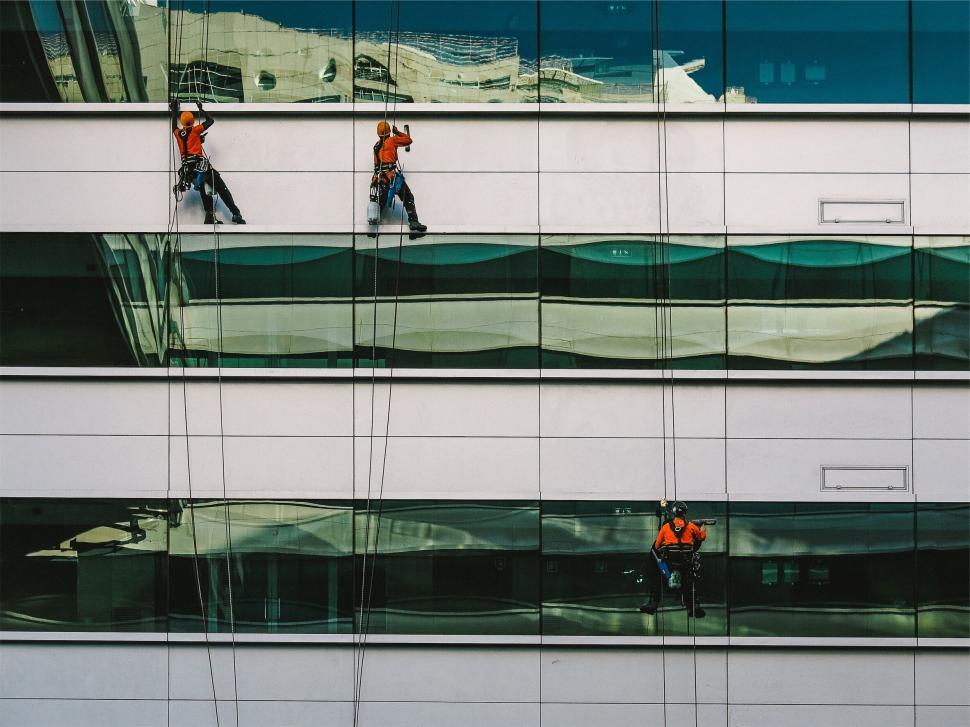 Free Image of Workers on the glass windows of a high-rise building 