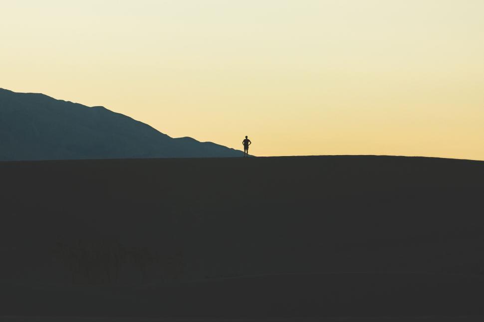 Free Image of Silhouetted figure on a dune at sunset 