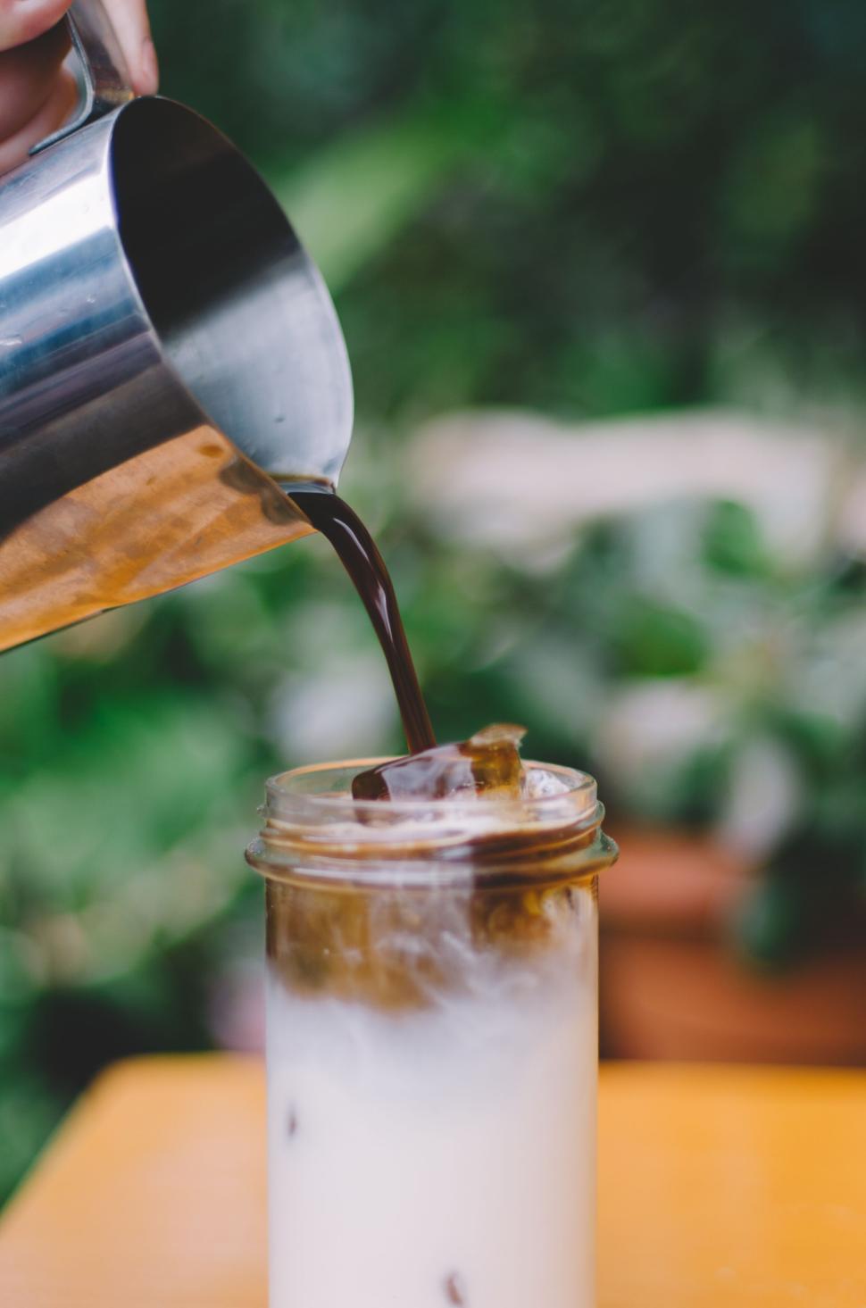 Free Image of Pouring cold brew coffee into glass with iced milk. 