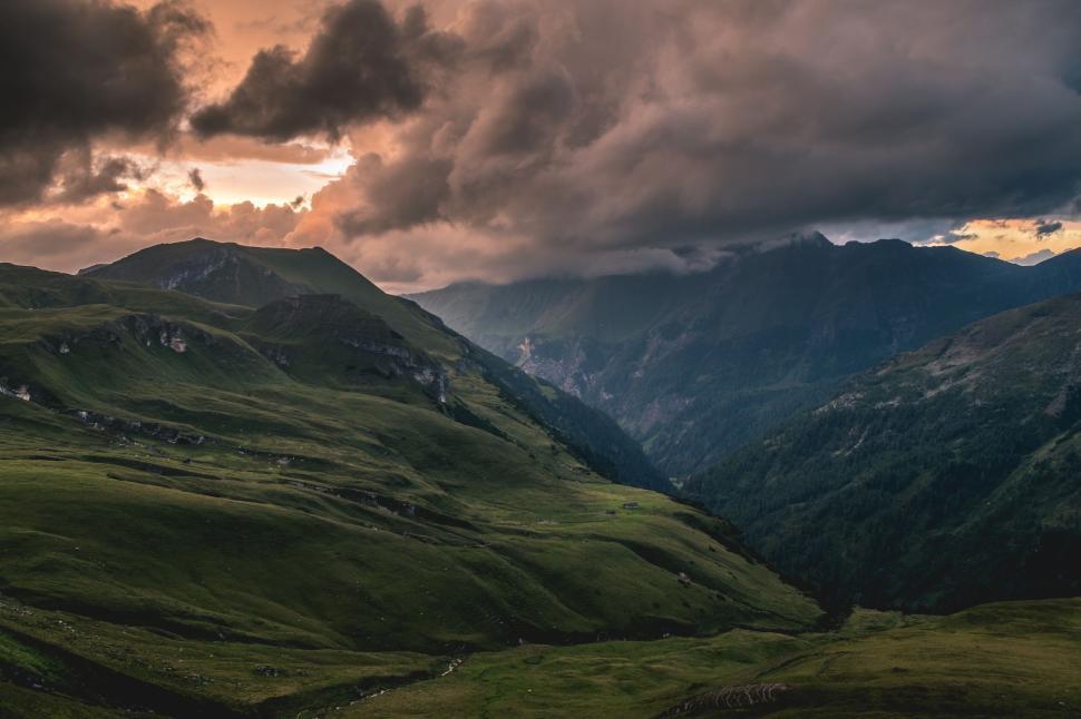Free Image of Dramatic sunset over mountains with rolling green hills. 