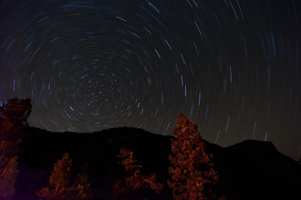 Free Image of Star trails over mountain landscape with pine trees 
