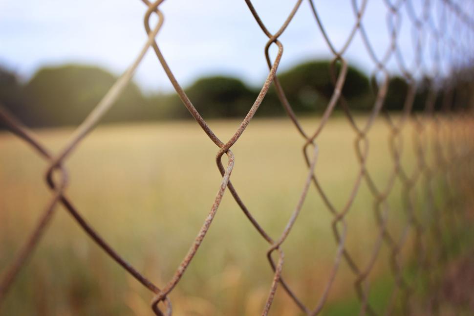Free Image of Rusty metal fence in a field under cloudy sky 