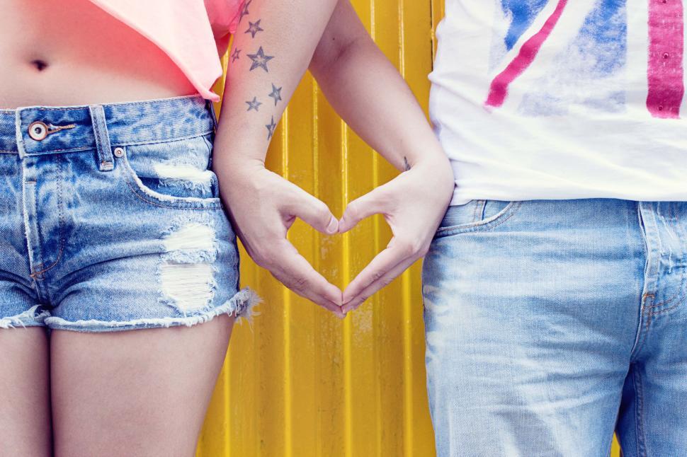Free Image of Hands forming heart shape with denim shorts background. 