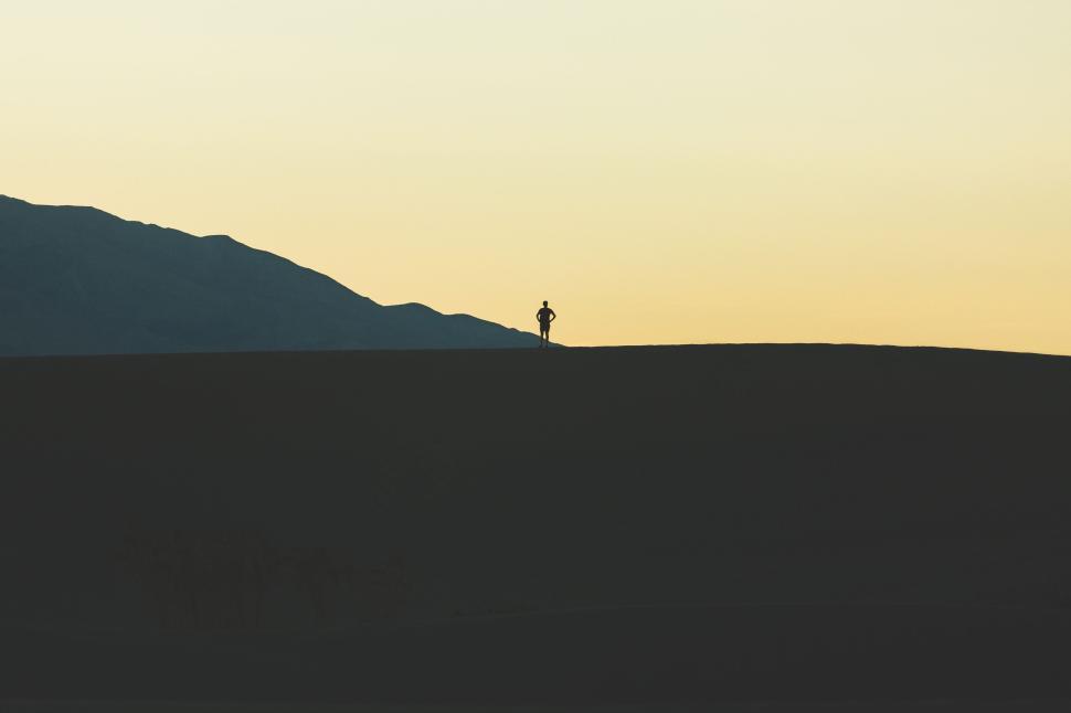 Free Image of Lone silhouette of person on desert hill at sunset 