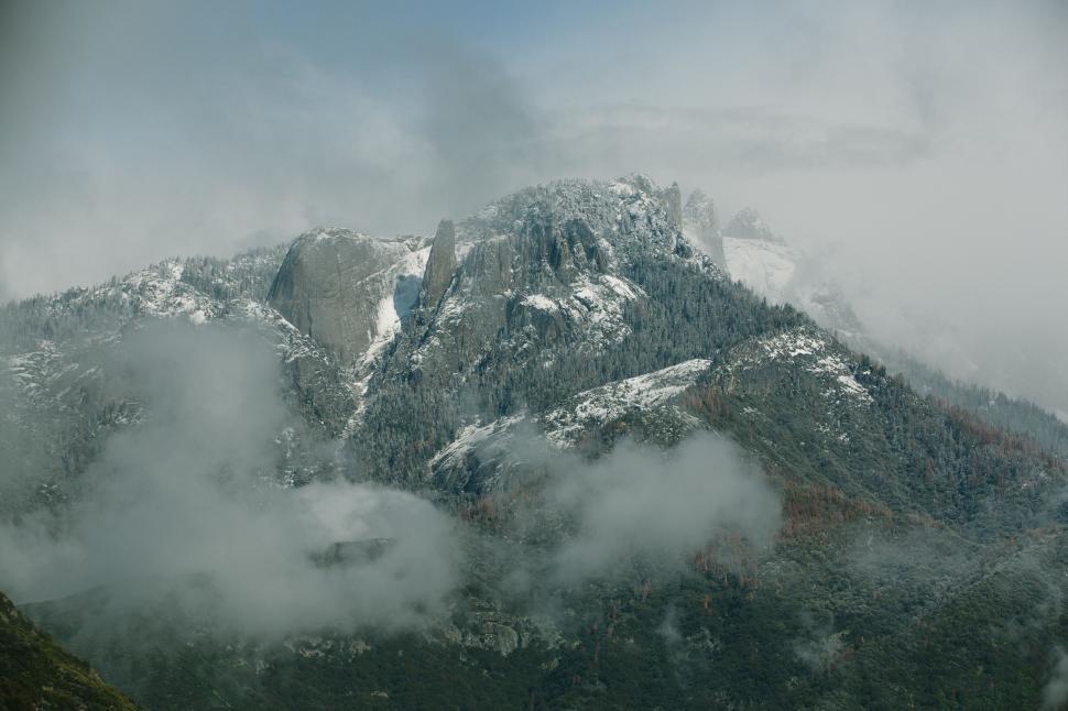 Free Image of Snow-capped mountains with fog and rugged terrain 