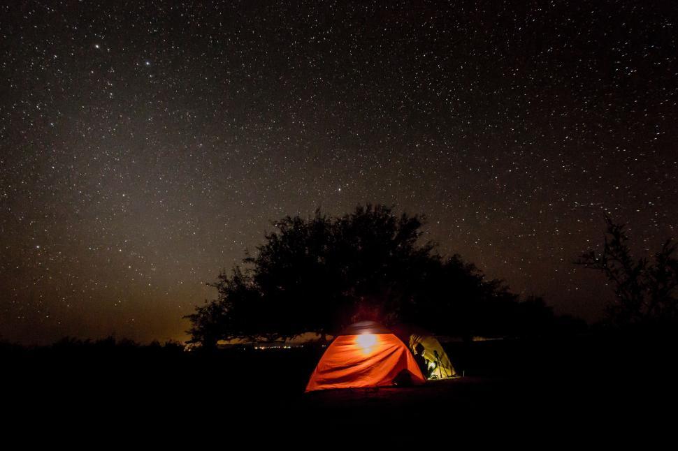 Free Image of Tent illuminated at night under a star-studded sky 