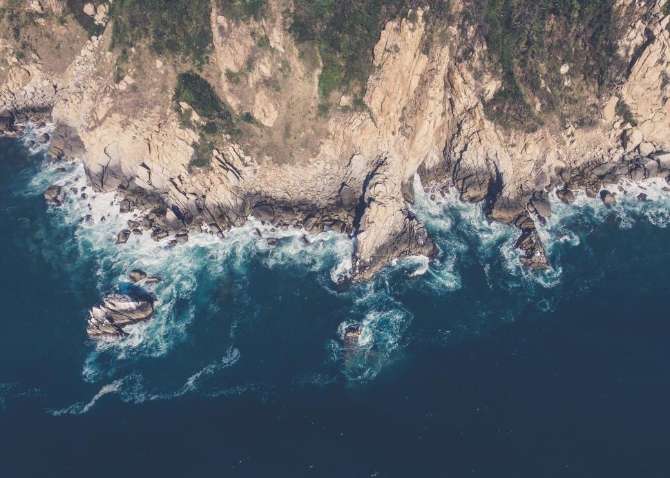 Free Image of Aerial view of rugged coastal cliffs with waves below 