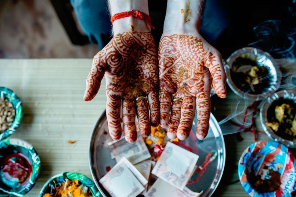 Free Image of Henna-decorated hands over traditional plate ceremony 