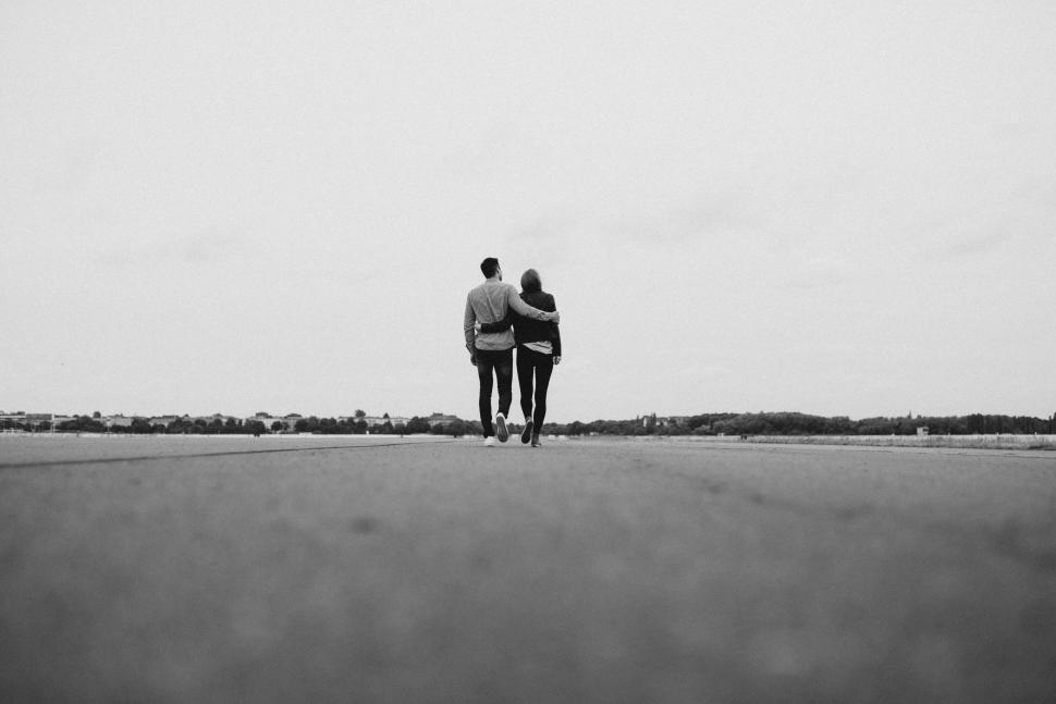Free Image of Monochrome couple walking on deserted open road 