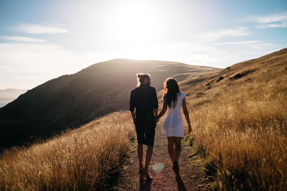 Free Image of Couple walking on a path surrounded by golden fields 