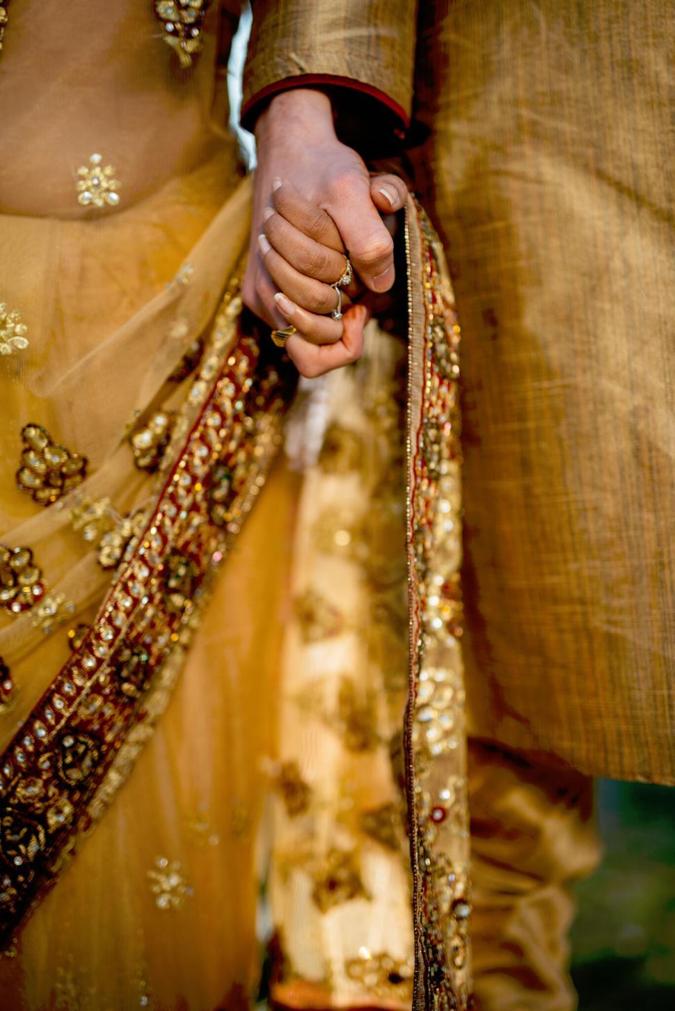 Free Image of Close-up of couple holding hands in detailed traditional attire. 