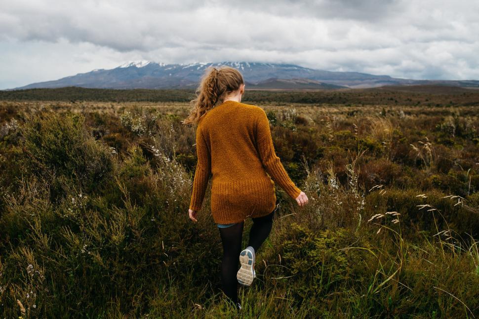 Free Image of Woman hiking in scenic landscape with mountains behind 