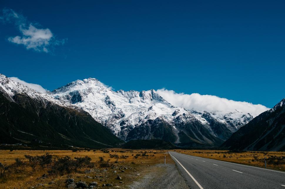 Free Image of Empty road leading to snowy mountains under blue sky 