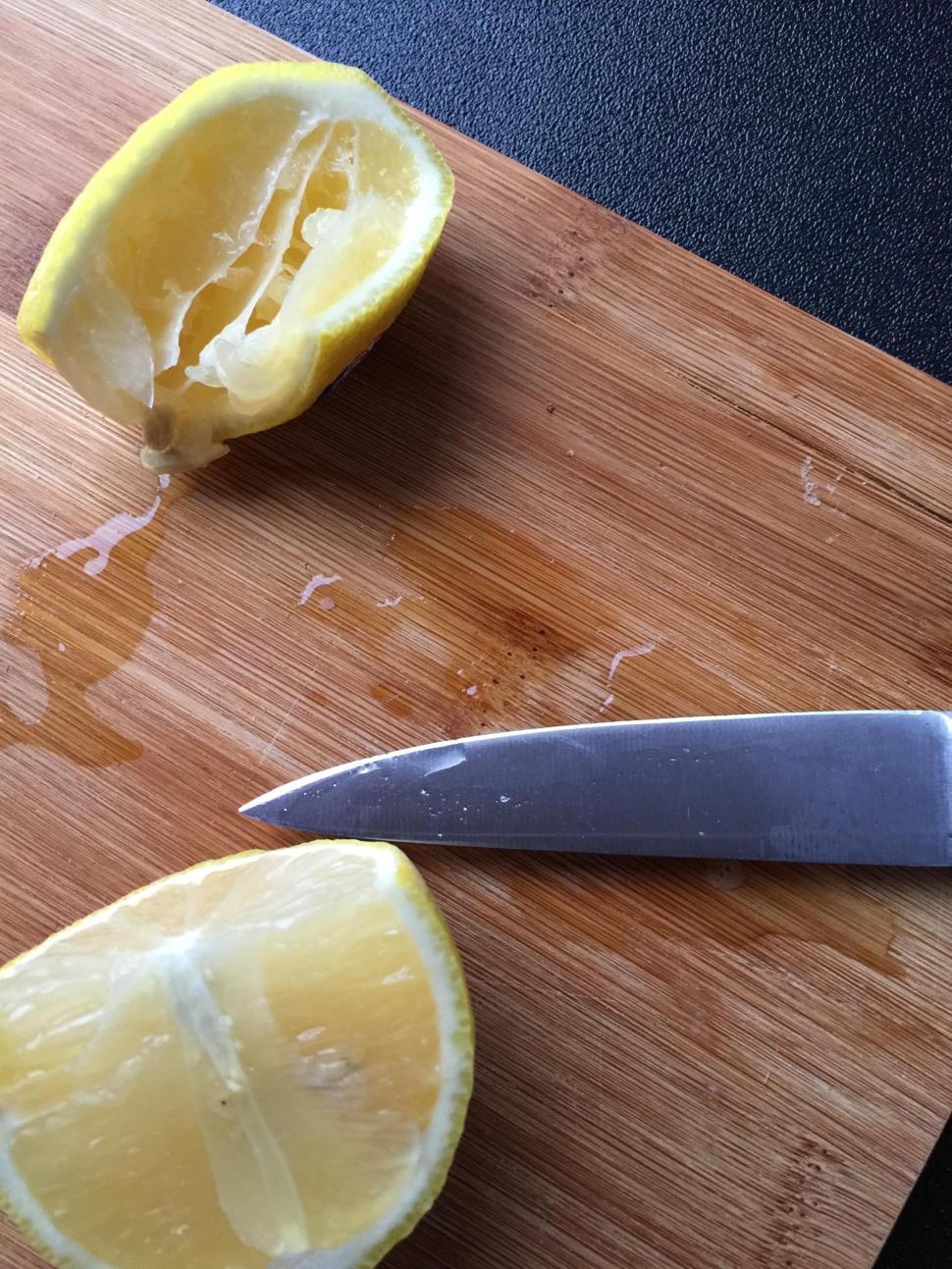 Free Image of Sliced lemon on wooden cutting board with knife, fresh zest. 