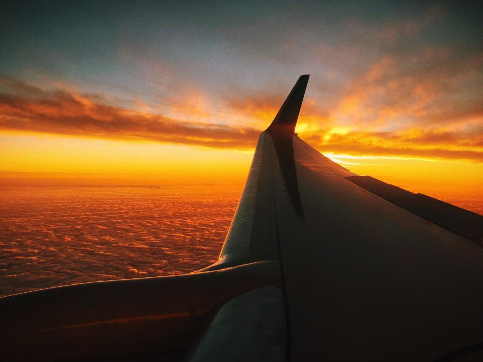 Free Image of Sunset view from airplane window with wing visible. 