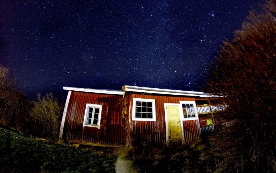 Free Image of Starry night sky over an old wooden house in countryside 