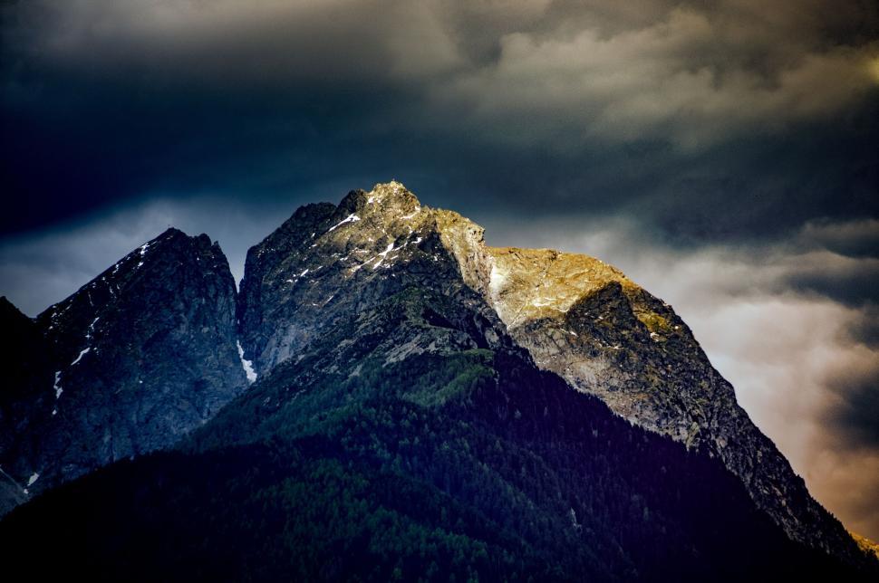 Free Image of Majestic mountain peaks under a dramatic cloudy sky. 