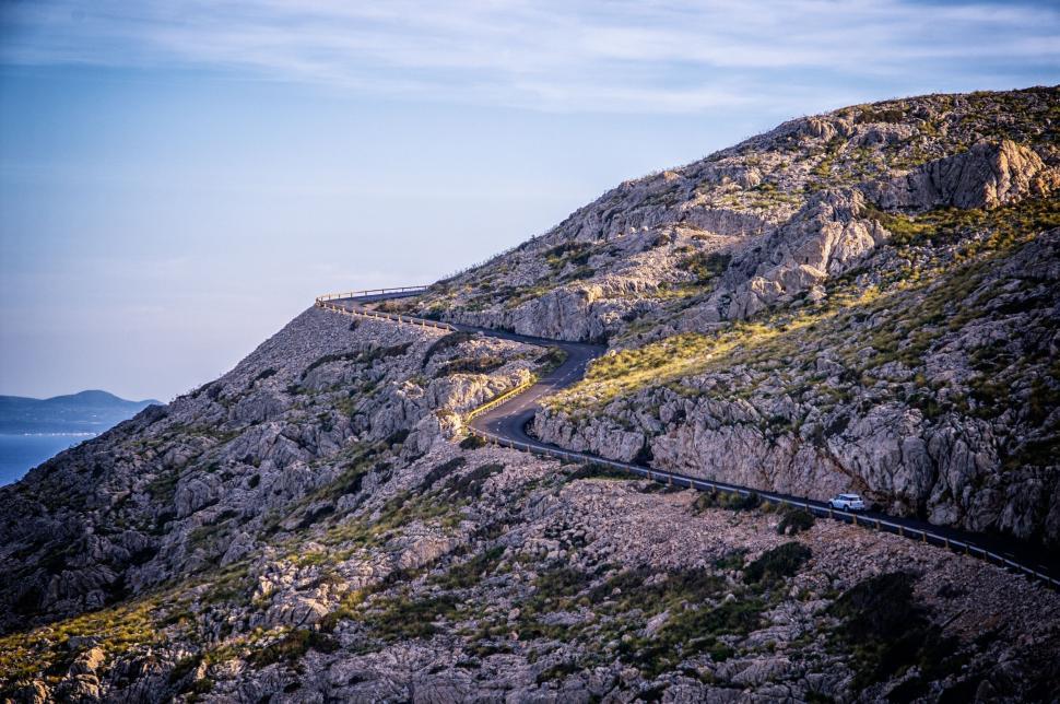 Free Image of Winding mountain road with a lone vehicle view 