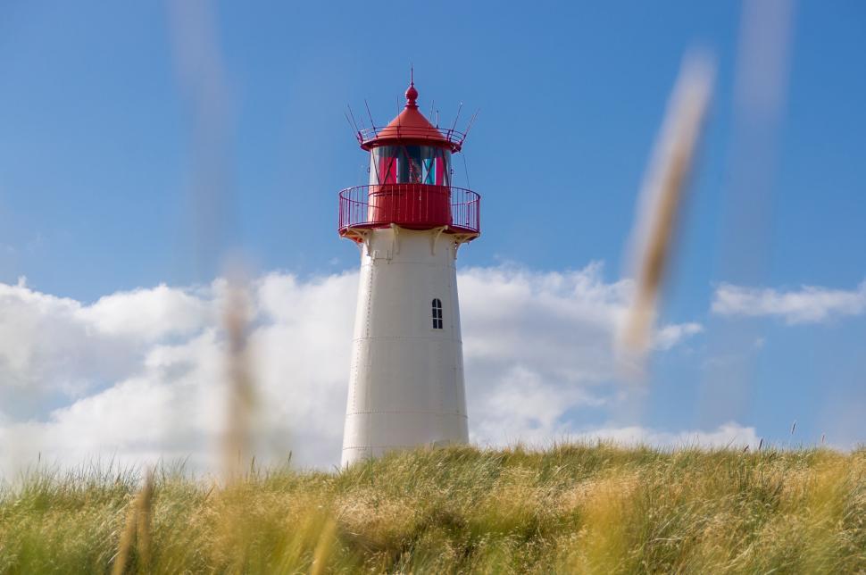Free Image of White and red coastal lighthouse standing tall 