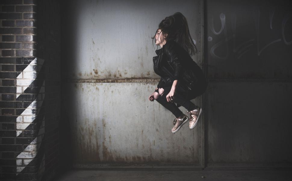 Free Image of A person in mid-air dressed in black jacket jumps high. 