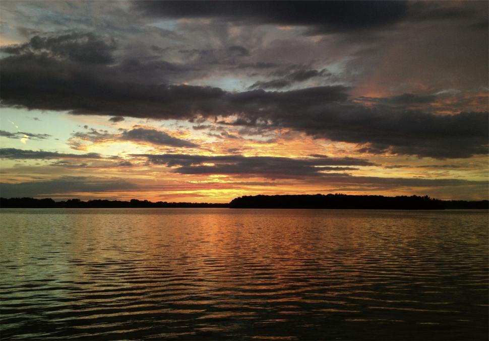 Free Image of Stunning sunset over calm lake with colorful sky and water. 